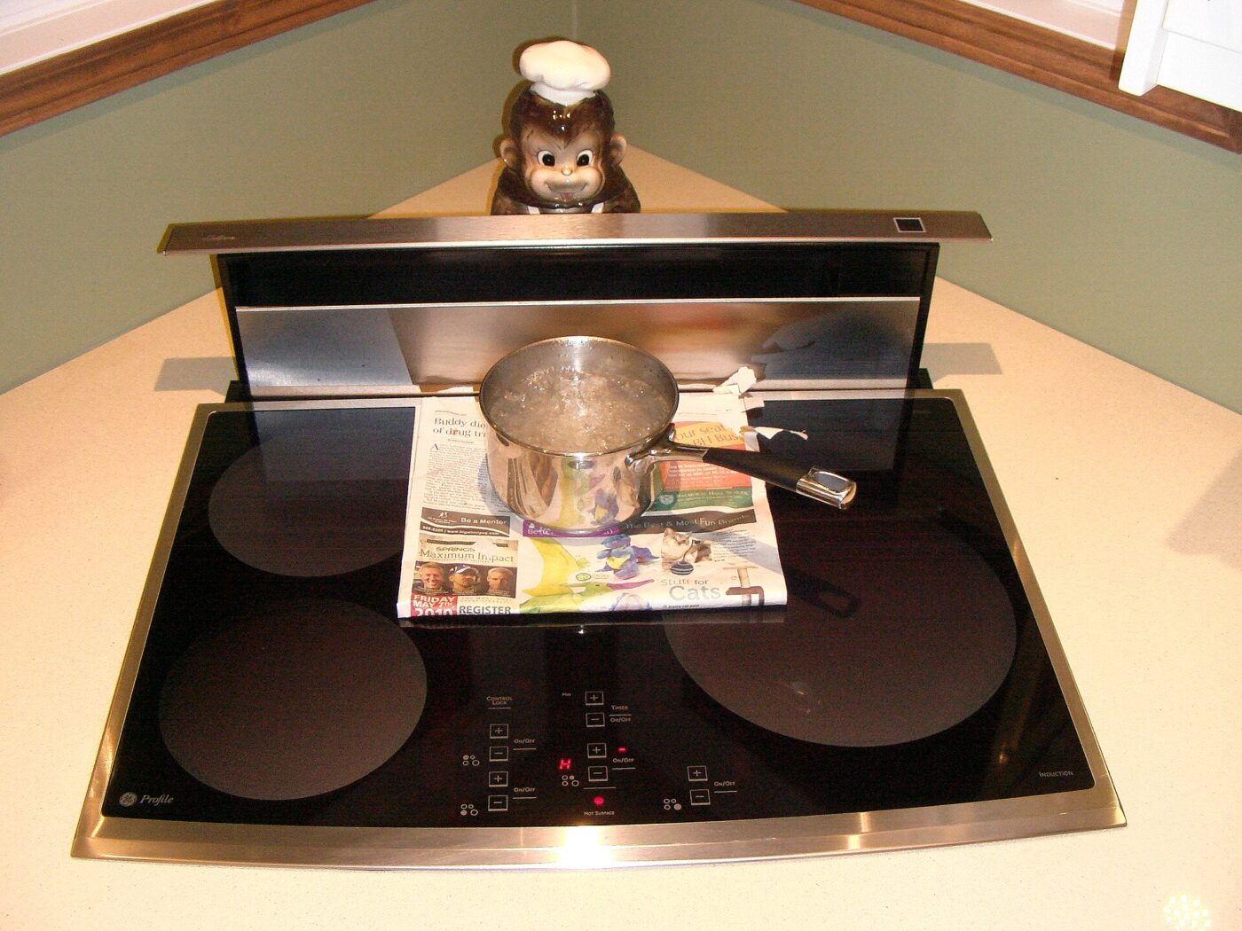 Water boils in a steel pot resting on newspaper on an induction cooktop, which heats the pan directly