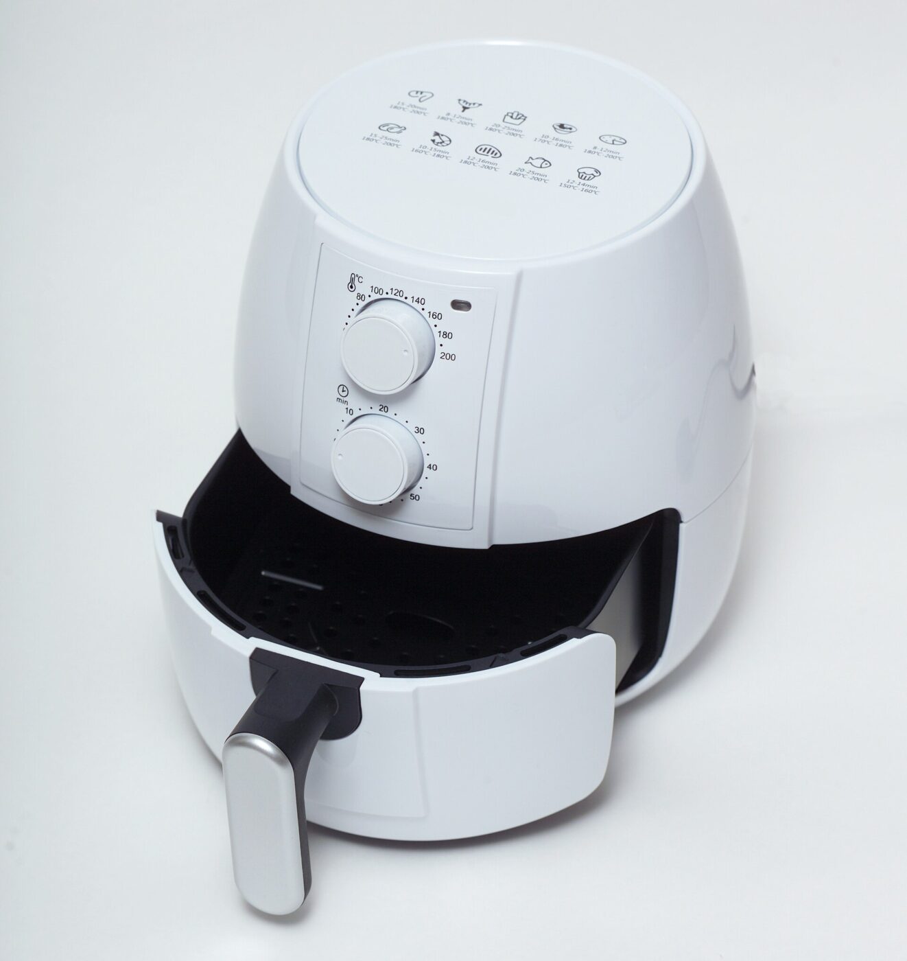 A white air fryer on a plain background with its basket drawer pulled open.