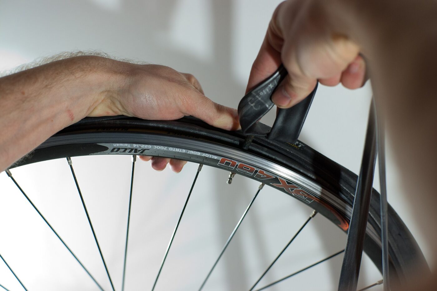 Hands pull a black inner tube out from under a road bike tire.