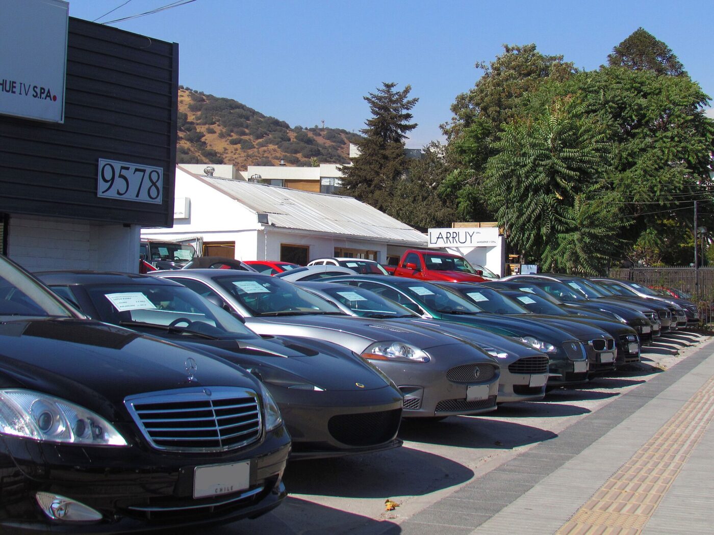 Rows of used cars with signs in their windshields lined up at a dealership lot