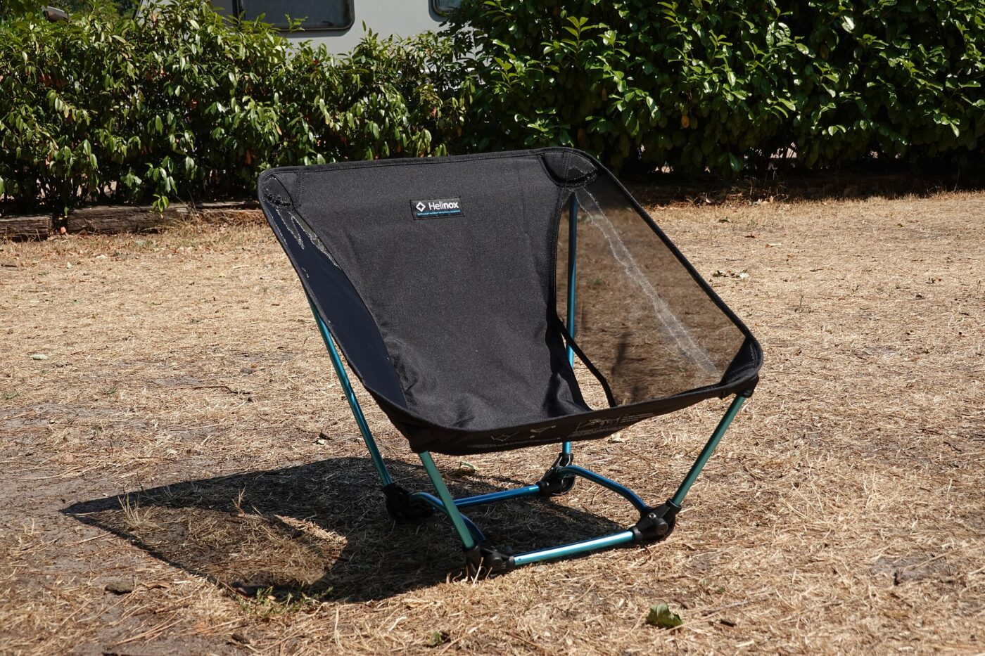 A low folding camp chair with a thin aluminum frame and mesh seat on open ground
