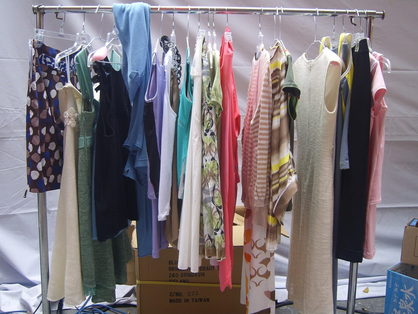 Dresses and tops on a rolling garment rack above stacked cardboard shipping boxes