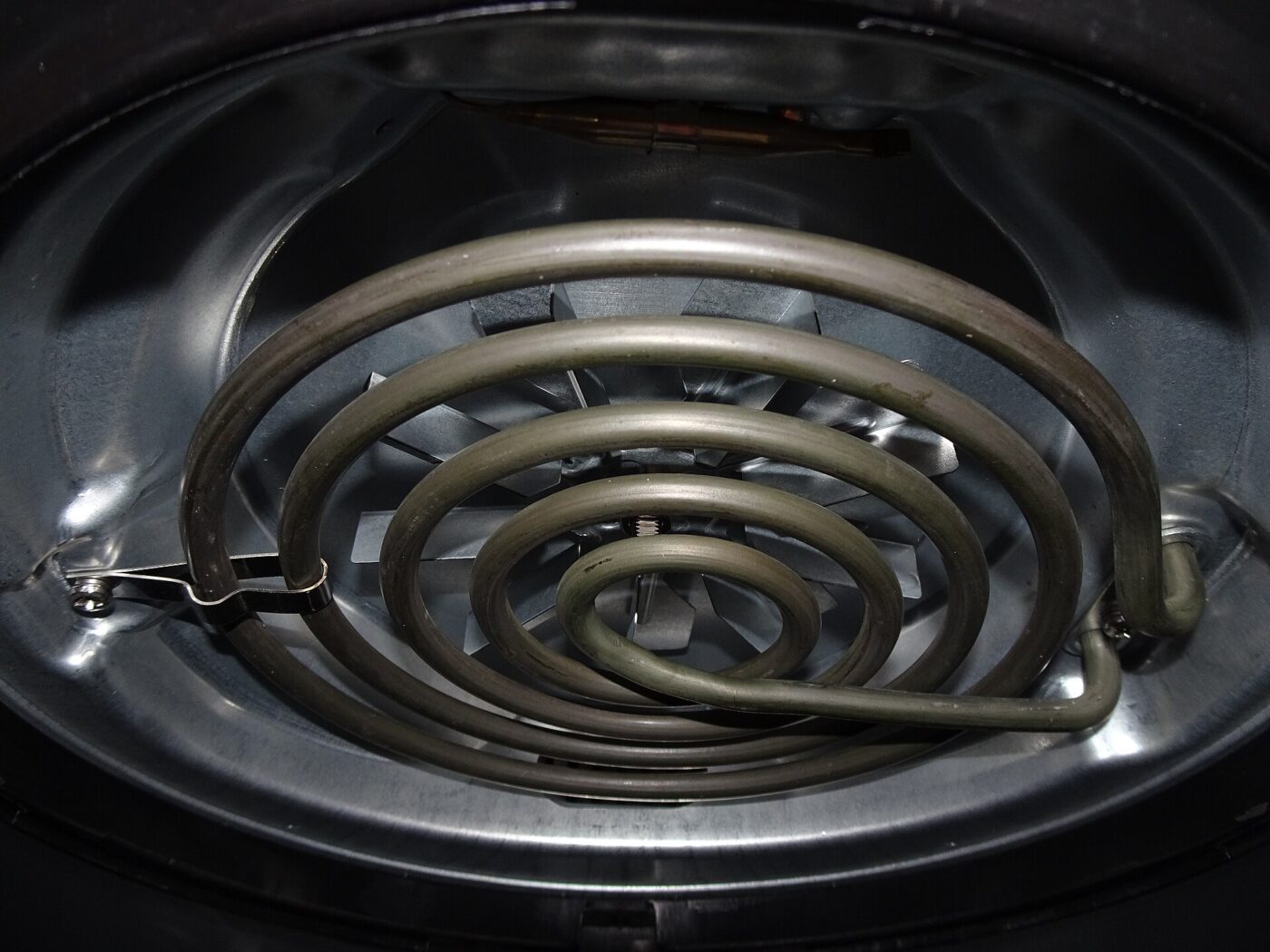 The coiled heating element and fan of an air fryer, seen inside the open appliance.