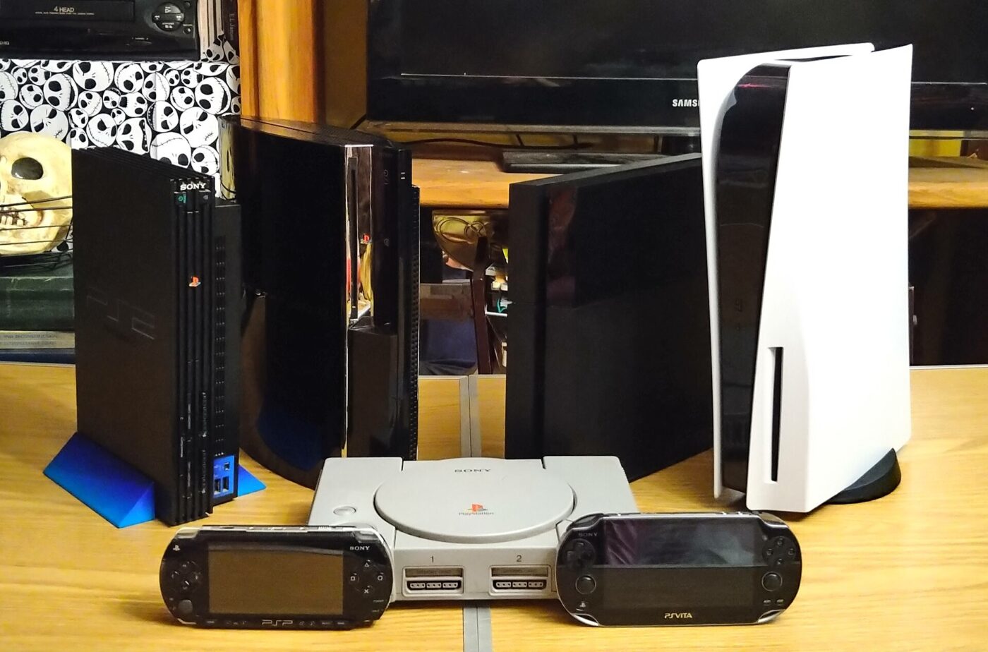 PlayStation consoles from several generations lined up on a desk, with a white PS5 at the right