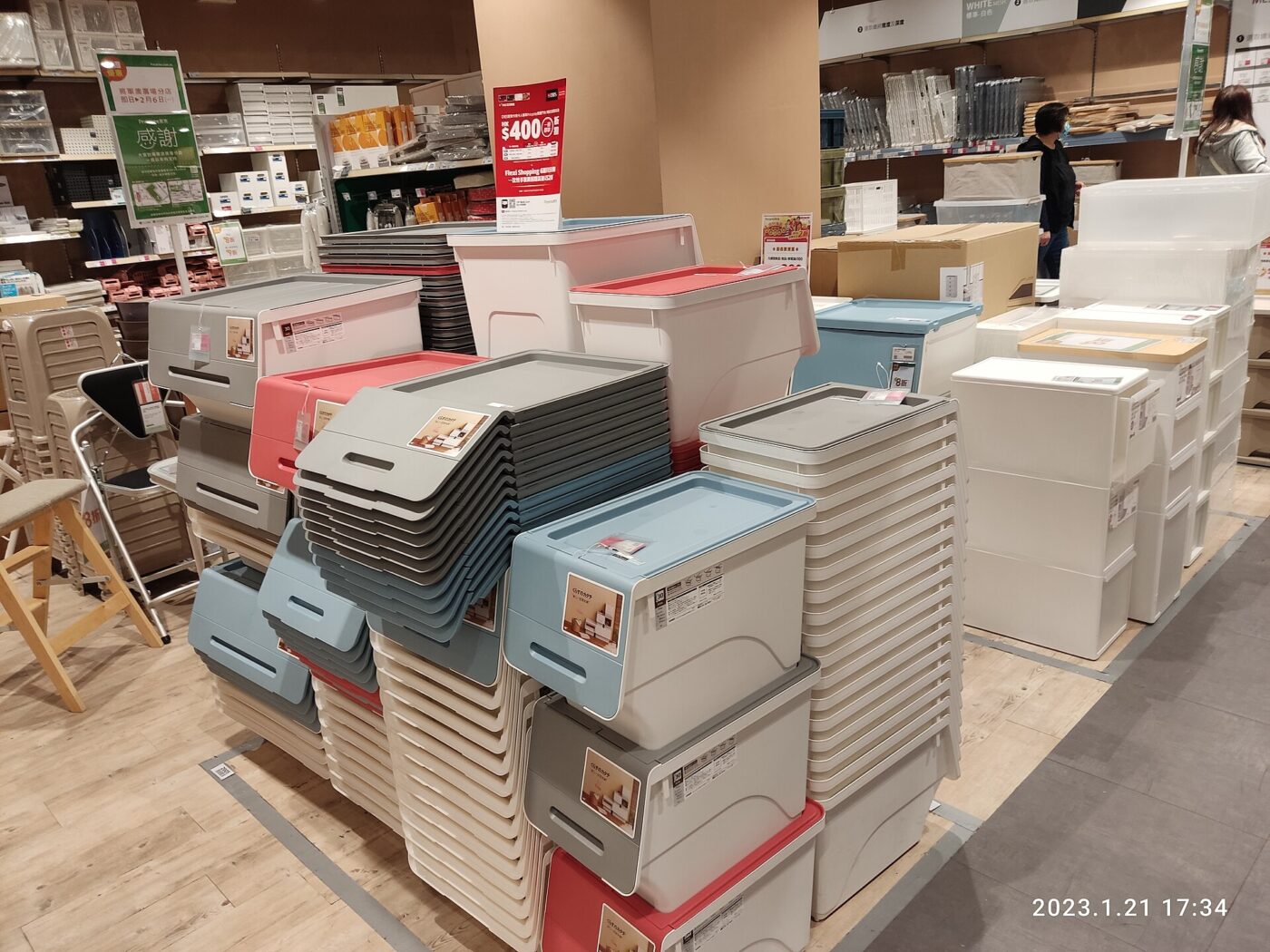 Plastic storage boxes and lidded bins stacked for sale on a store floor.