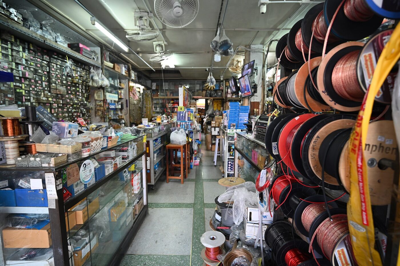 Spools of electrical wire stacked on racks in a crowded electronics parts shop