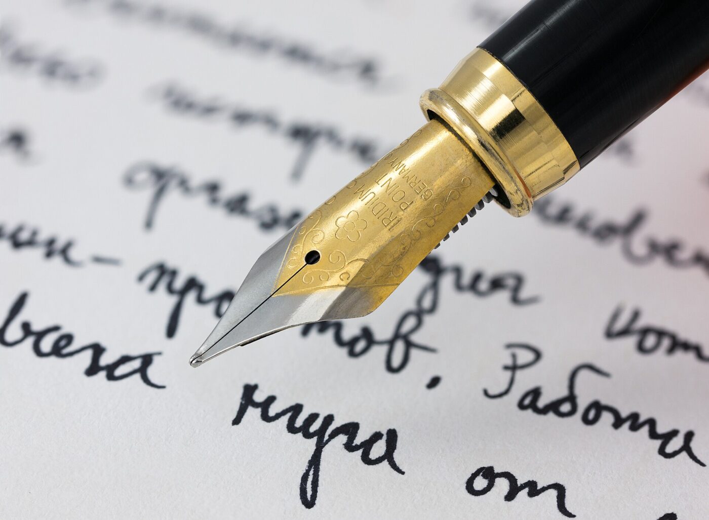 A fountain pen nib resting on a page of joined, handwritten script.