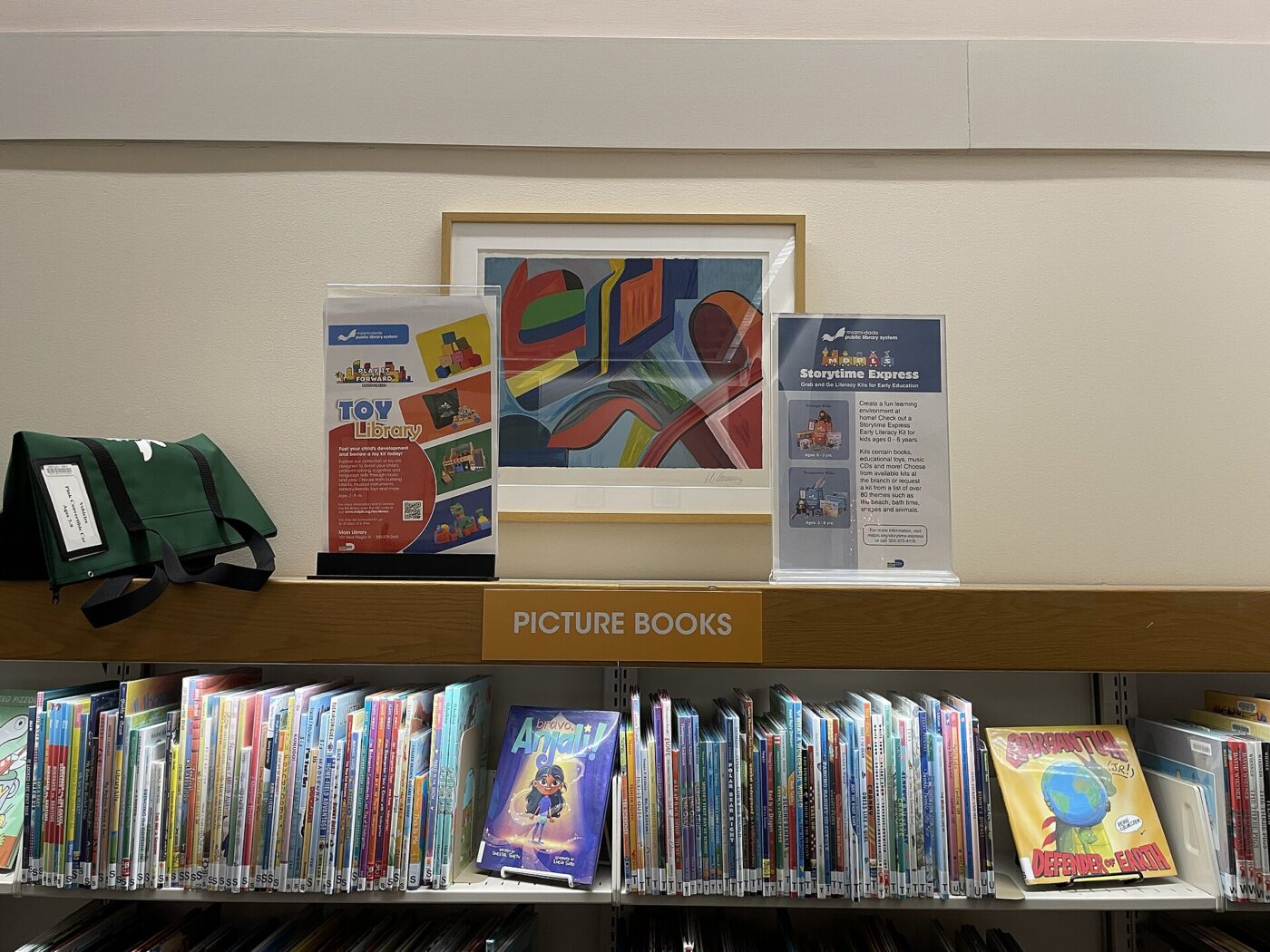 A public library shelf labeled picture books, filled with children's titles.