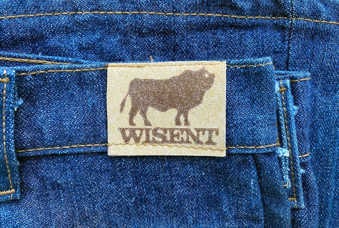 A stitched leather patch on the back waistband of a pair of blue jeans