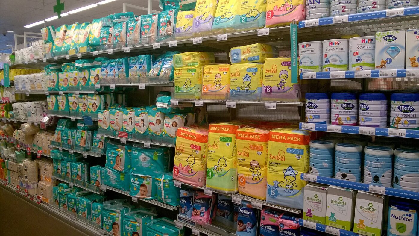 Packs of disposable diapers fill supermarket shelves beside tins of baby formula.