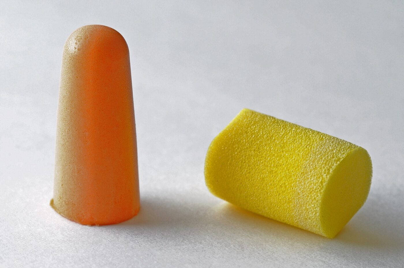 Two disposable foam earplugs, the kind sold with a rating printed on the package