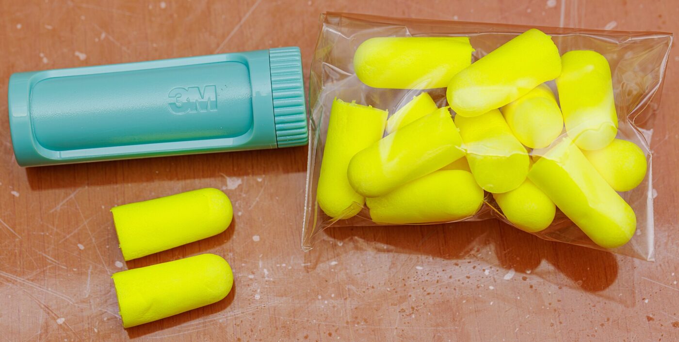 Disposable yellow foam earplugs in a bag, with a loose pair and a carrying case