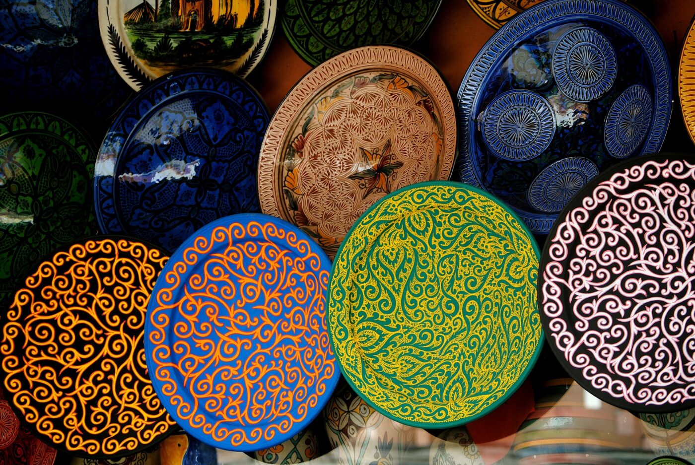 Hand-painted ceramic plates with swirling patterns in blue, green, yellow and pink on display