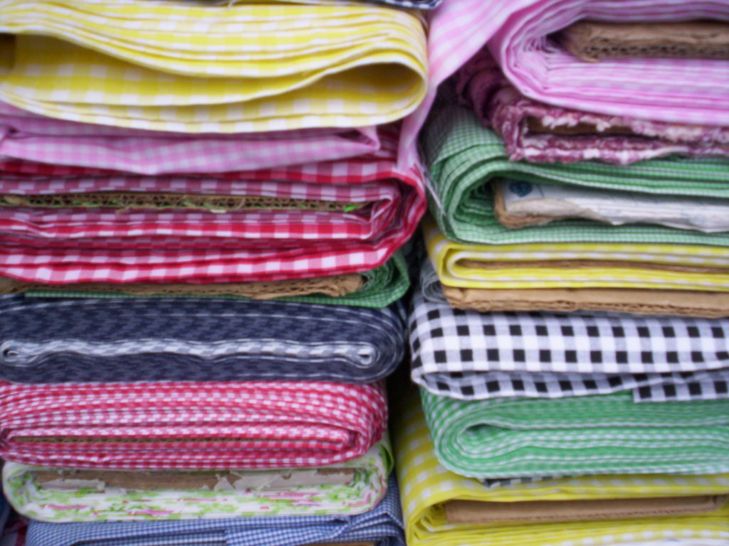Stacks of folded gingham and check fabric in pink, red, green, yellow and navy