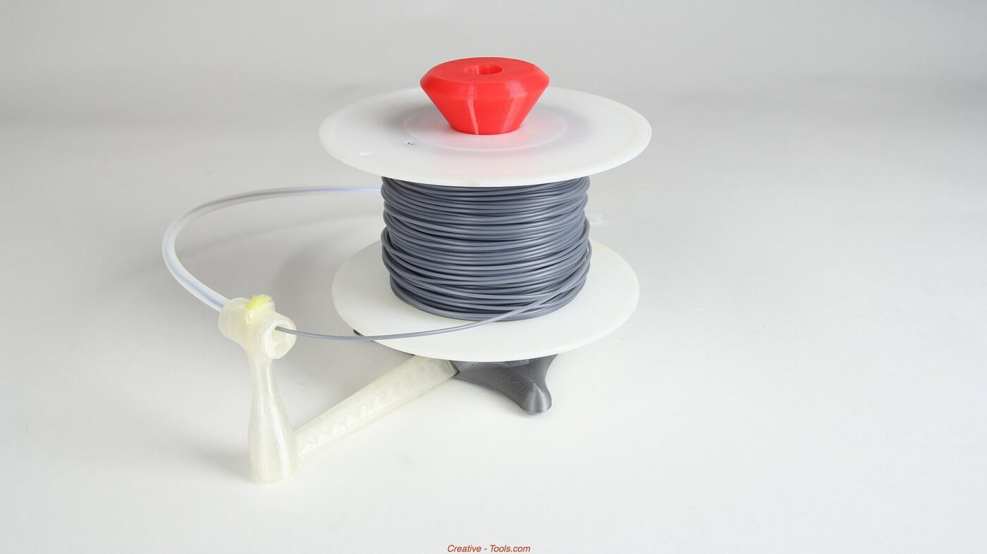 A coil of grey filament held between two flat plates on a printed holder.