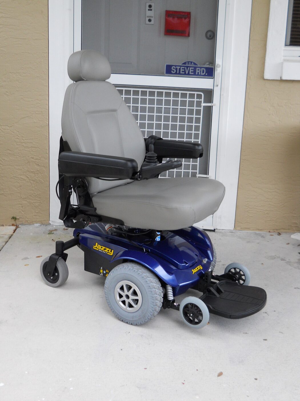 A power wheelchair parked at the front door of a house
