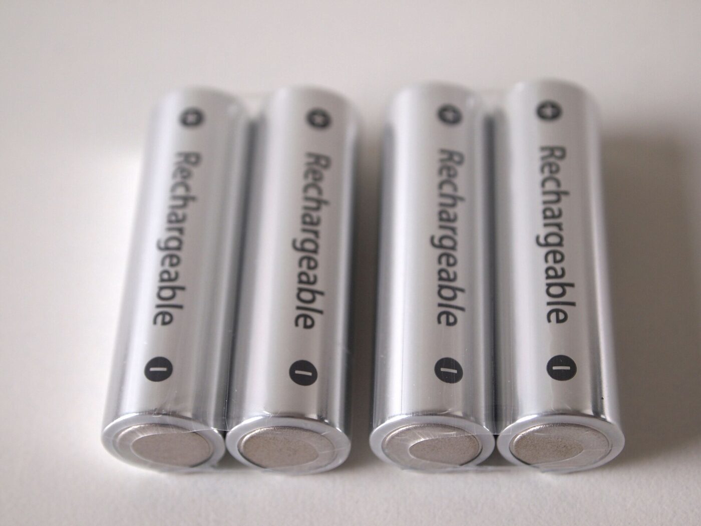 Four silver rechargeable AA cells lying side by side on a plain white surface