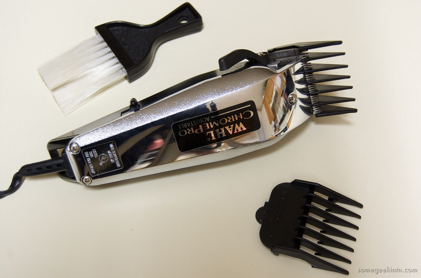 Chrome corded hair clipper with plastic guide combs and a small cleaning brush