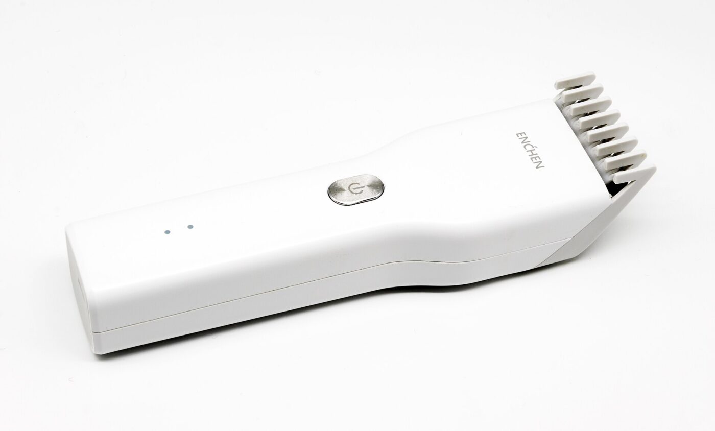 White cordless hair clipper with a guide comb attached, shown on a white background