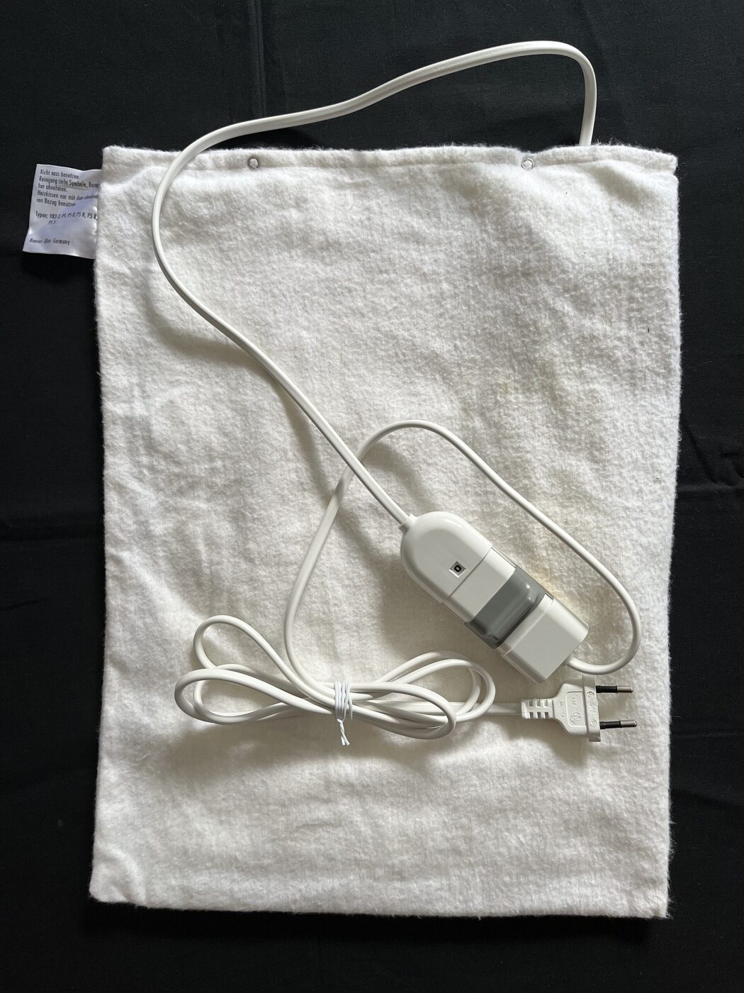 A folded electric underblanket laid flat, with its inline controller and power lead.