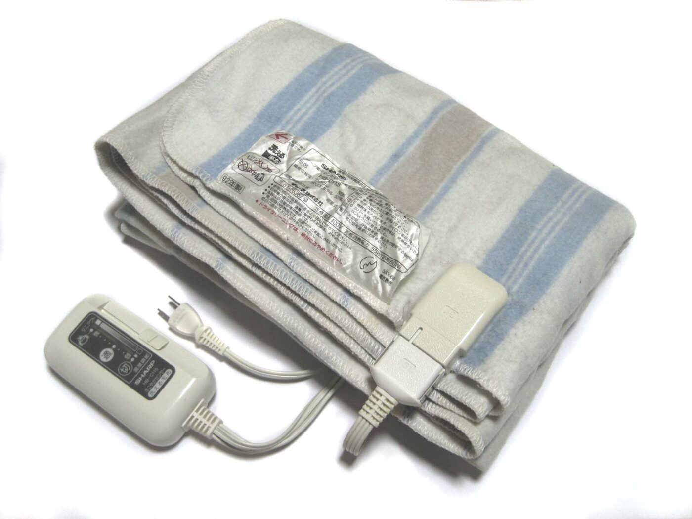 A folded striped electric blanket with its power cord and inline controller on white