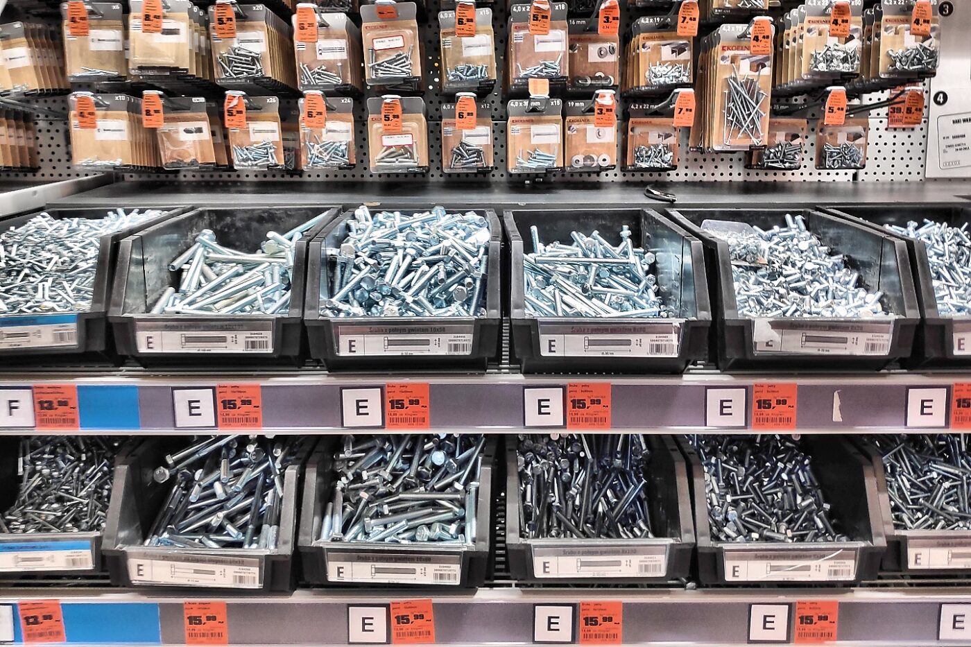 Bins of screws and bolts with price tags lining the shelves of a home improvement store
