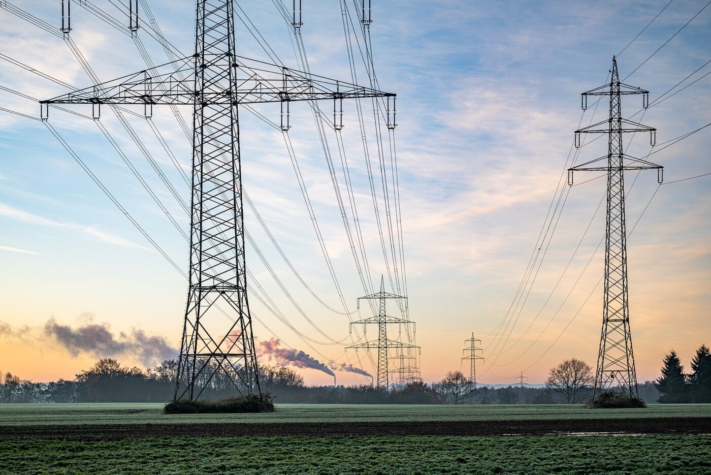 Two high-voltage transmission towers carrying power lines across open farmland.