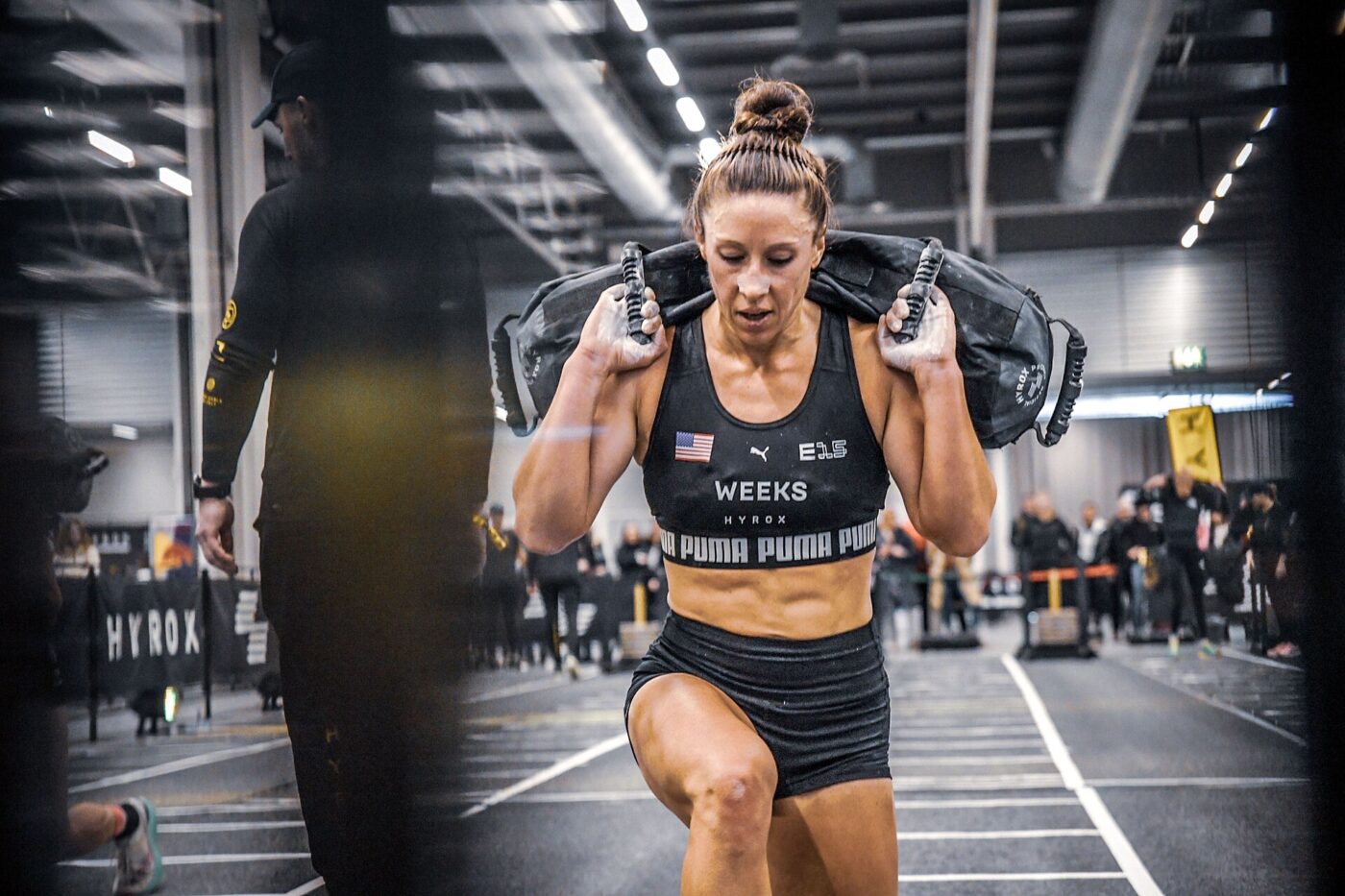 An athlete does walking lunges with a sandbag during a HYROX race in Stockholm