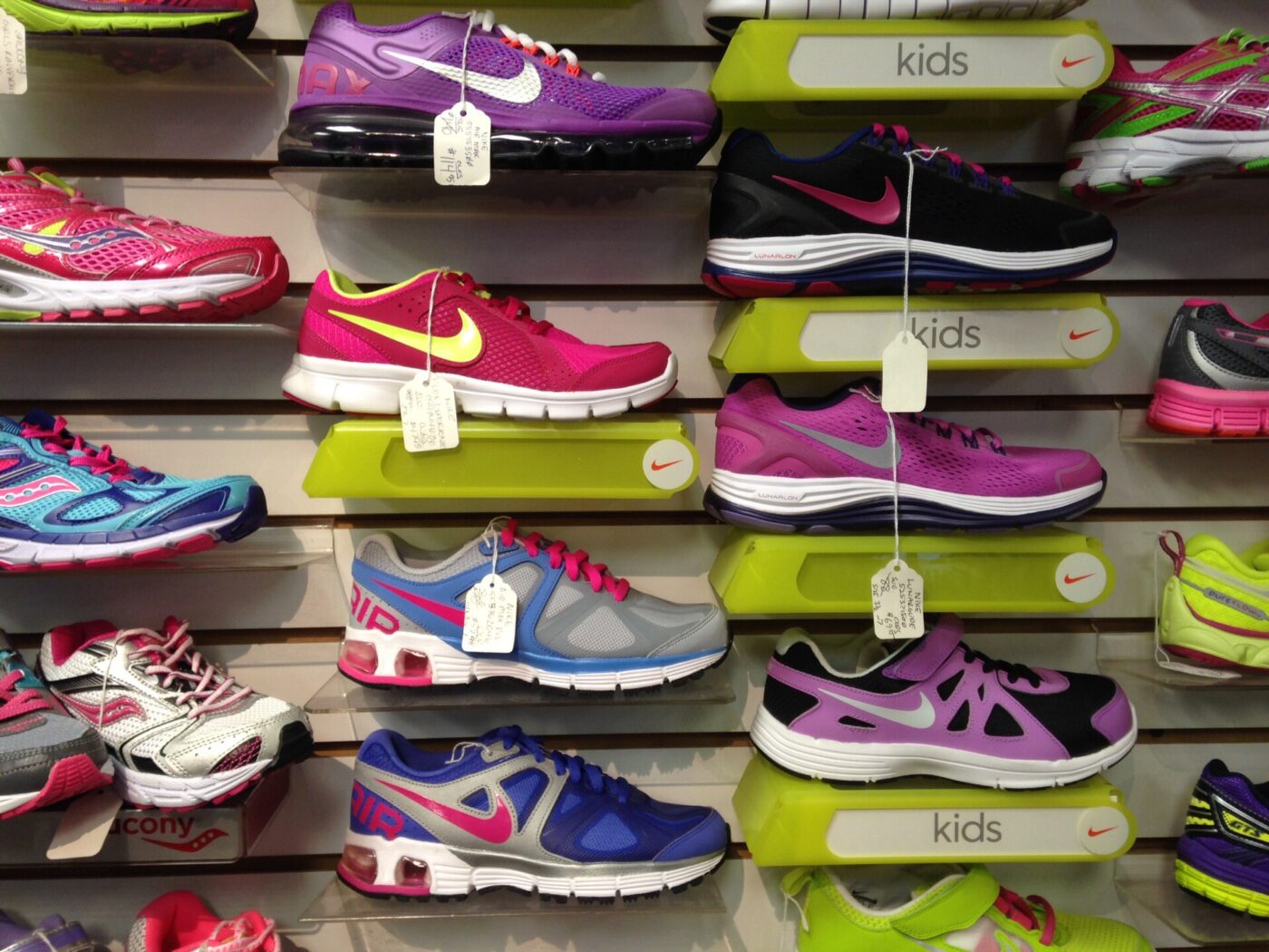 Children's athletic shoes with price tags on a store wall marked kids