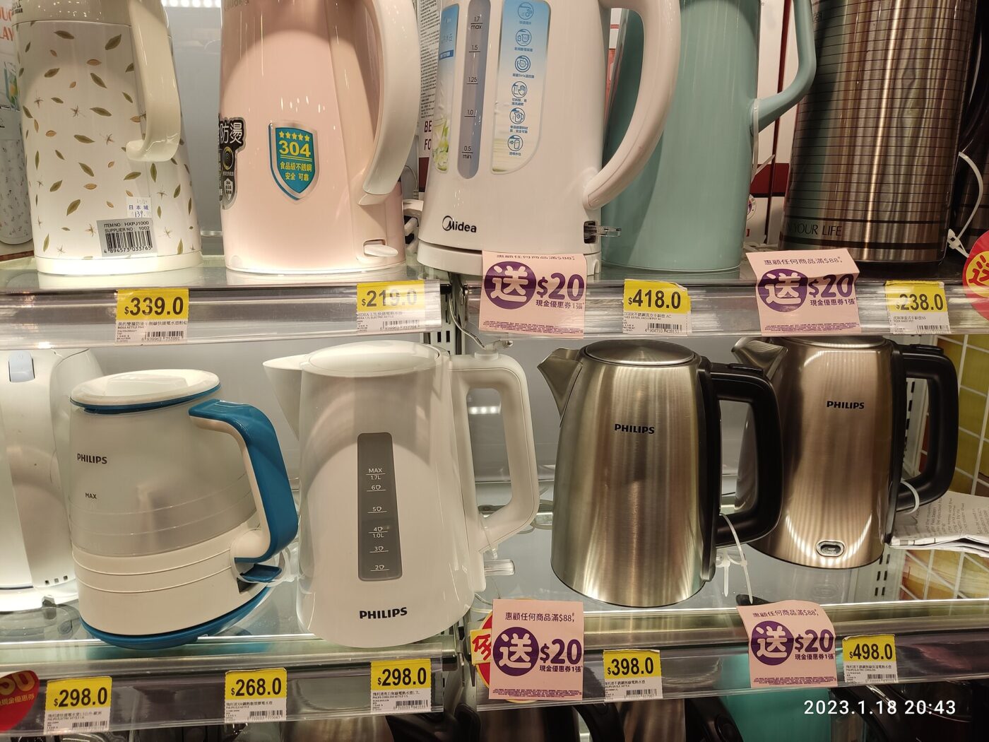 Electric kettles lined up on store shelves with price tags and promotional stickers
