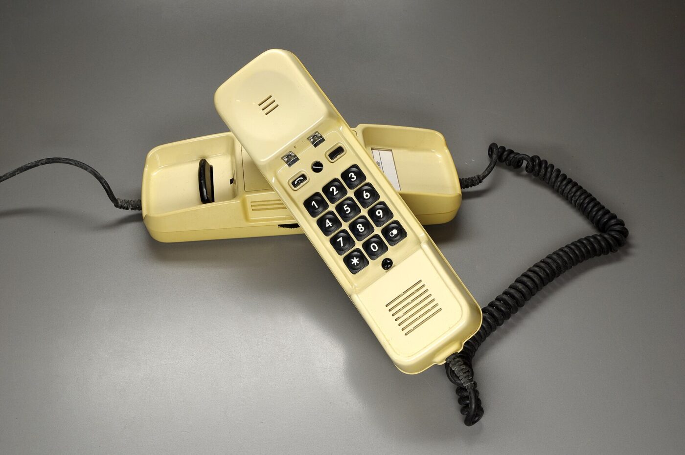 A cream corded push-button telephone with its handset lying beside the base.