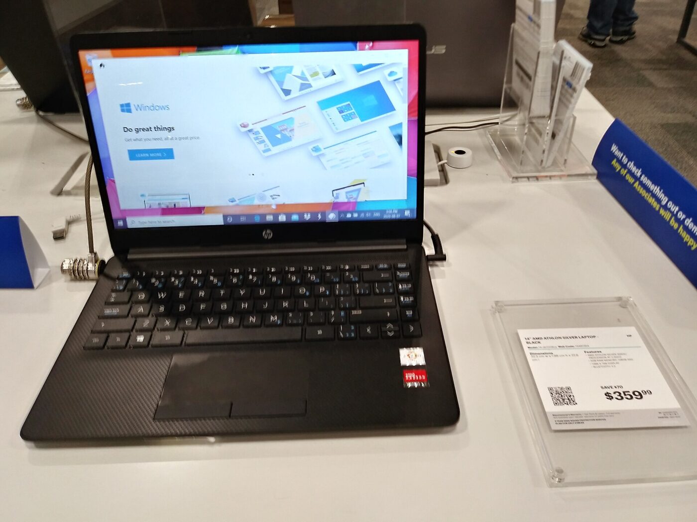 A laptop on a store display table beside its printed shelf price card