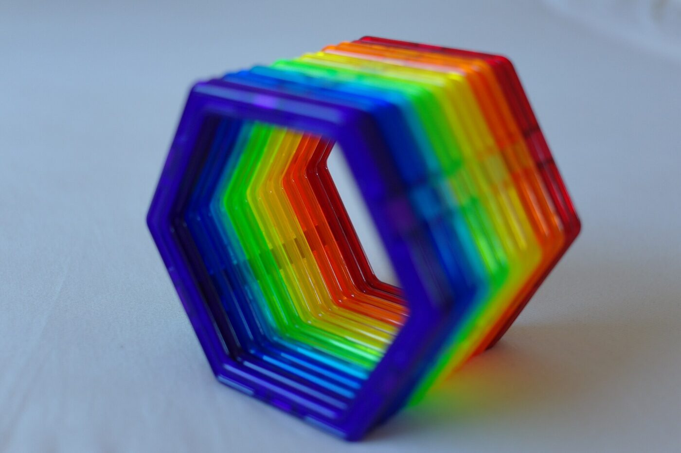 Translucent rainbow magnetic building tiles snapped together into a hexagonal ring.