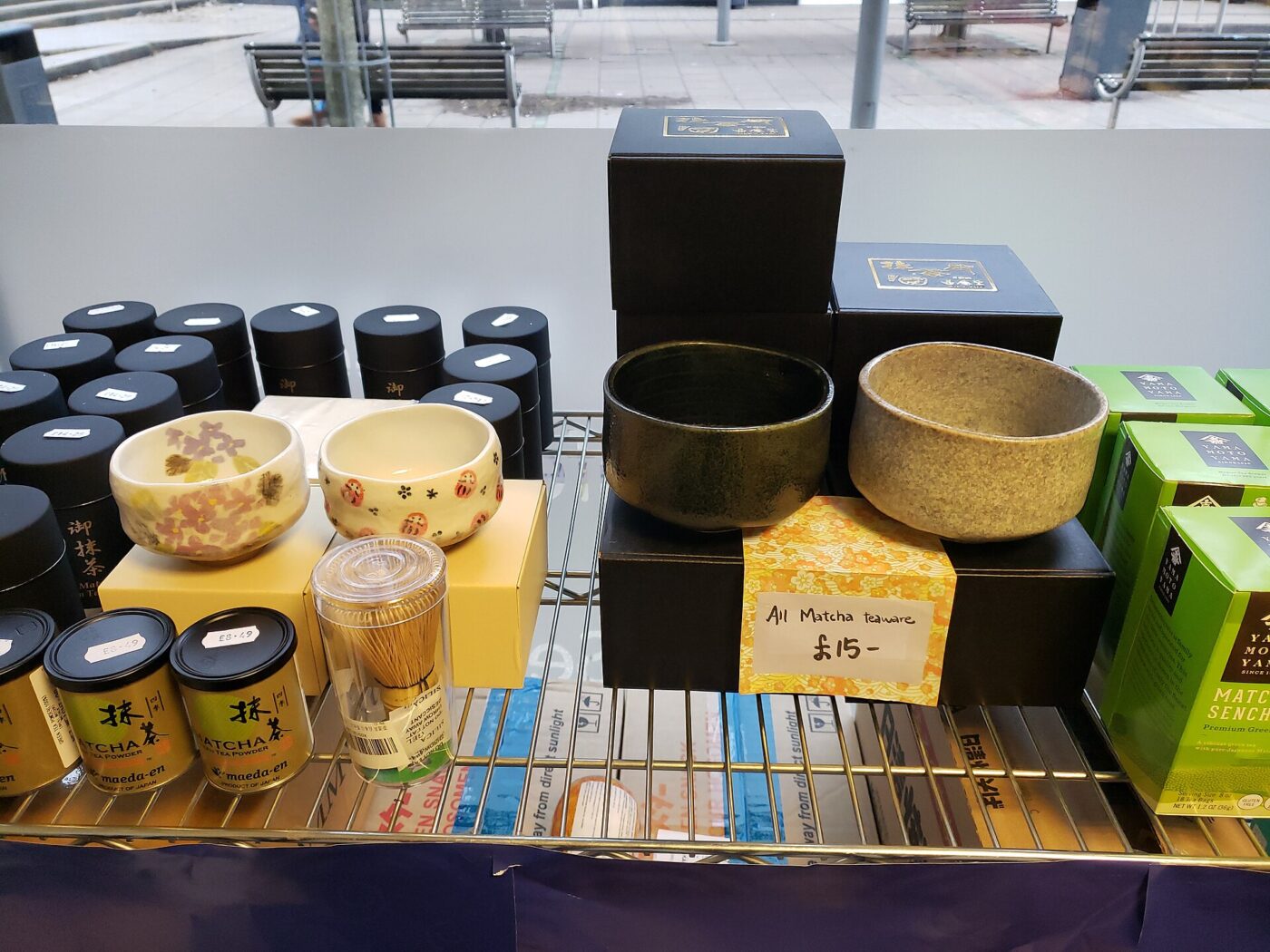 Tins of matcha, tea bowls and bamboo whisks displayed for sale on a shop shelf