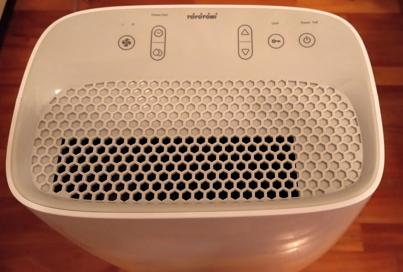 A compact white dehumidifier seen from above, showing its control buttons and vent grille.