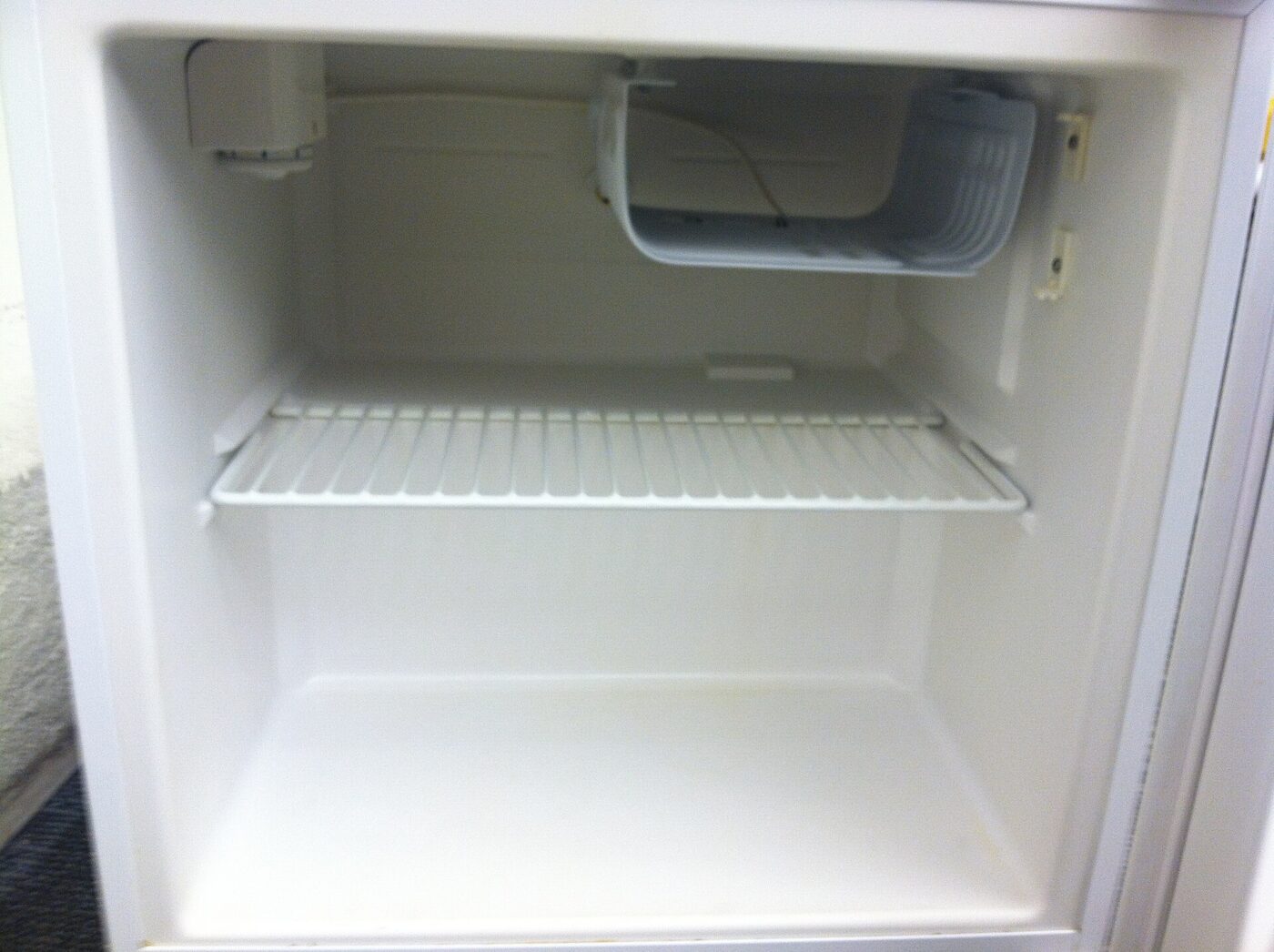 The upper chiller compartment inside a compact refrigerator, above a wire shelf.
