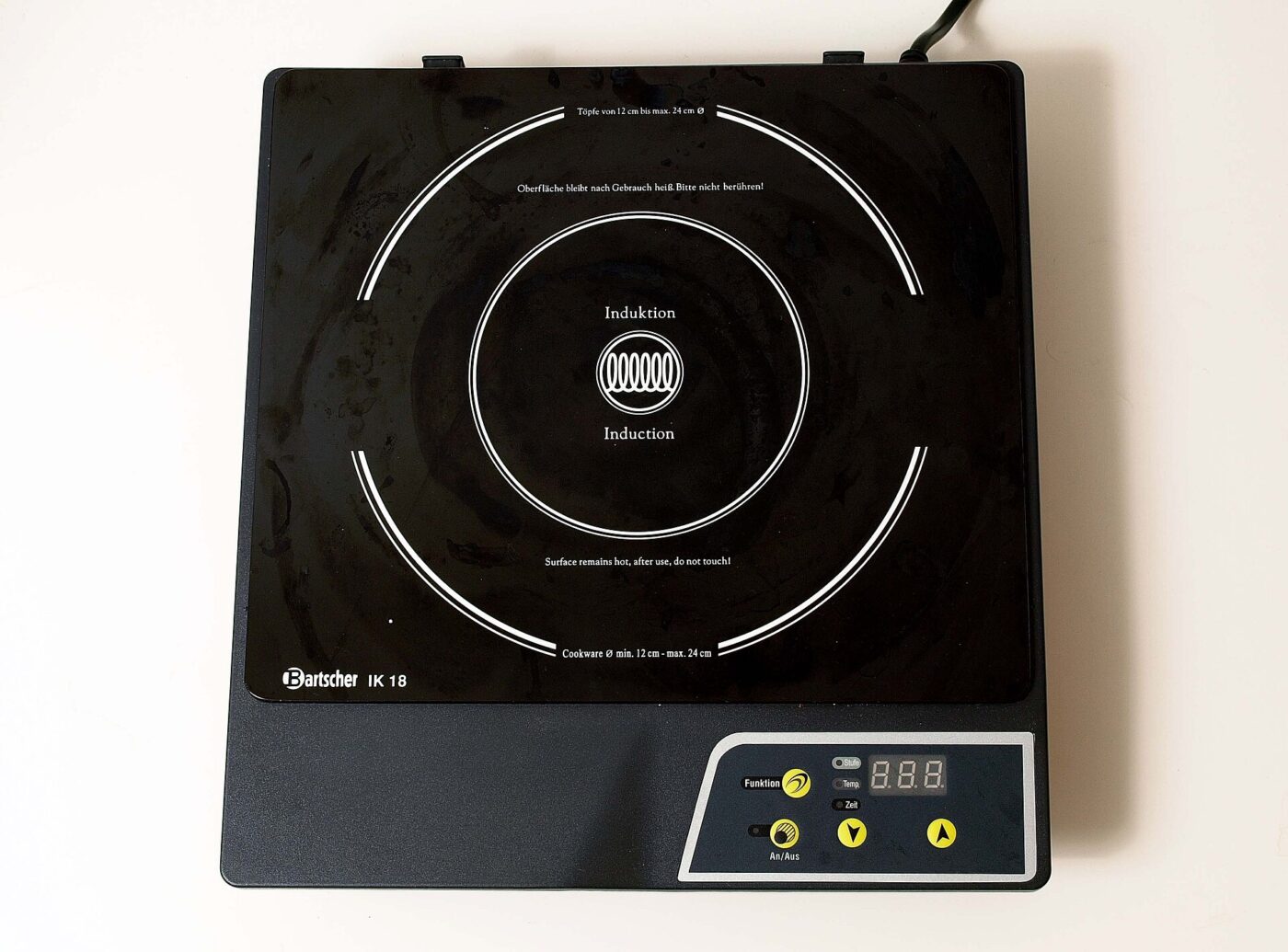 A portable induction plate with its warnings printed on the glass around the cooking zone.