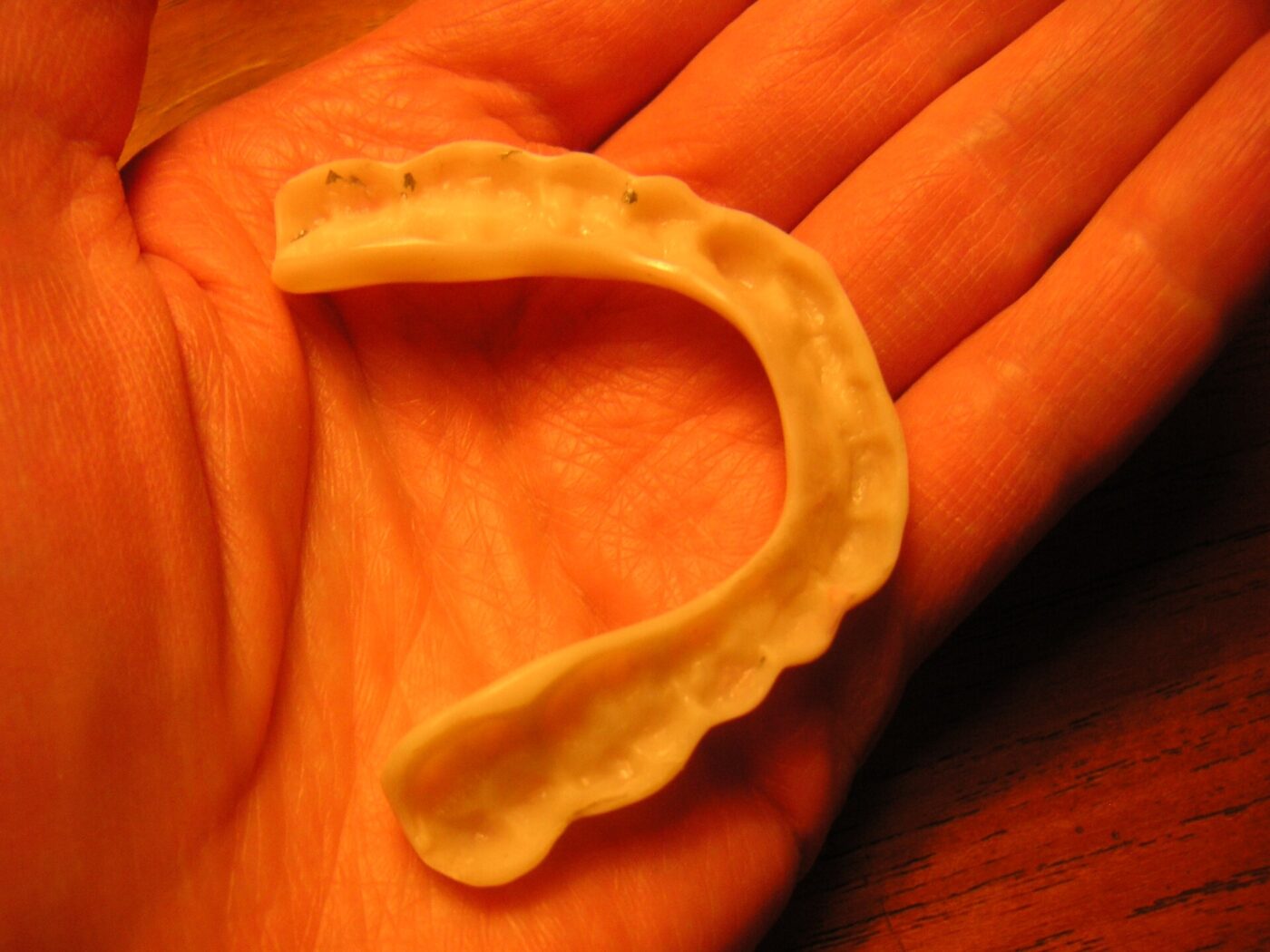 A molded orange mouthguard in close-up, showing the channel that fits over the teeth.