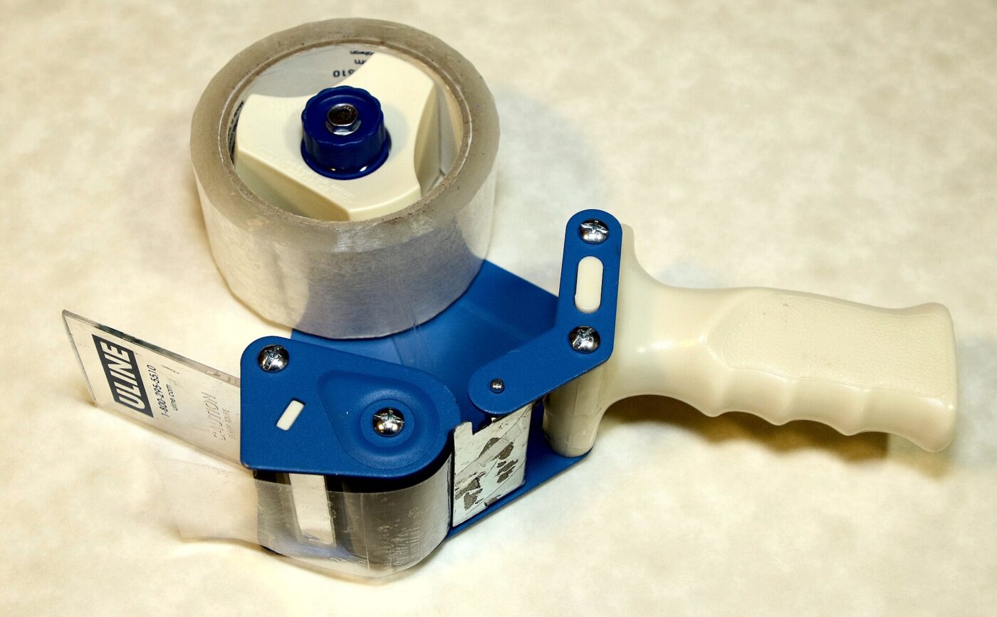 A handheld tape gun loaded with a roll of clear packing tape.
