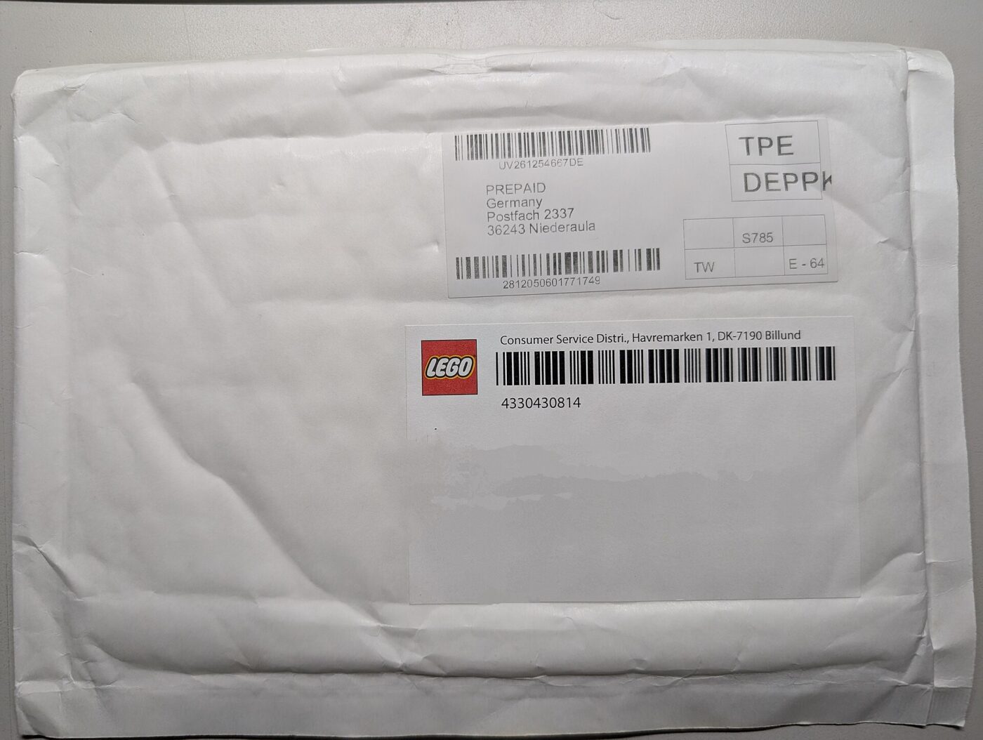 A padded mailer covered in prepaid postal and barcode labels, as delivered.