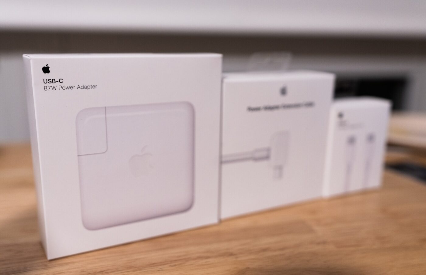 A USB-C power adapter and cable in their retail boxes on a wooden counter.