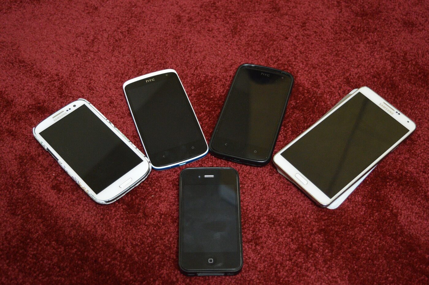 Five older smartphones from different makers laid out side by side.