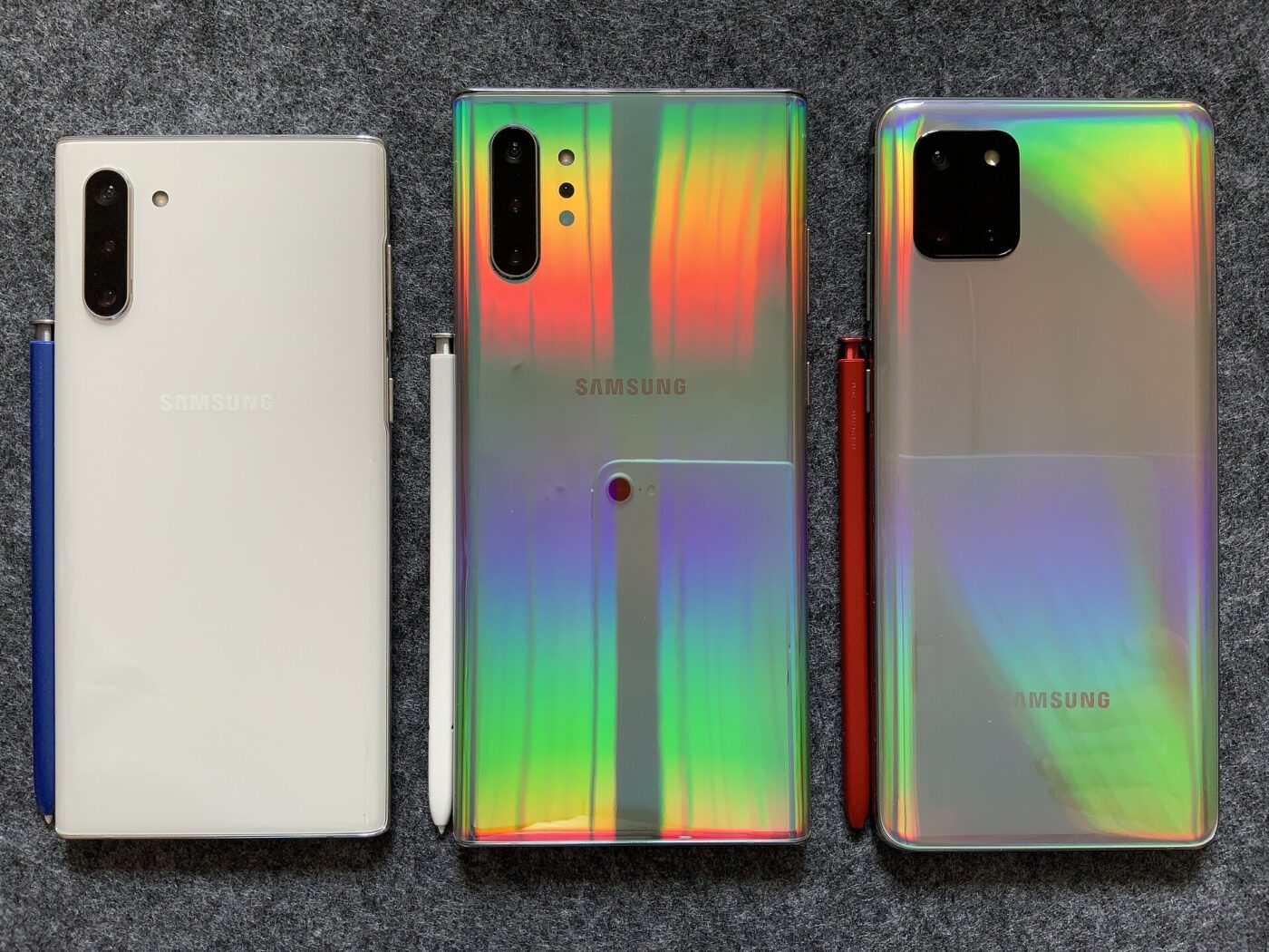 The backs of three smartphones lined up with their stylus pens.