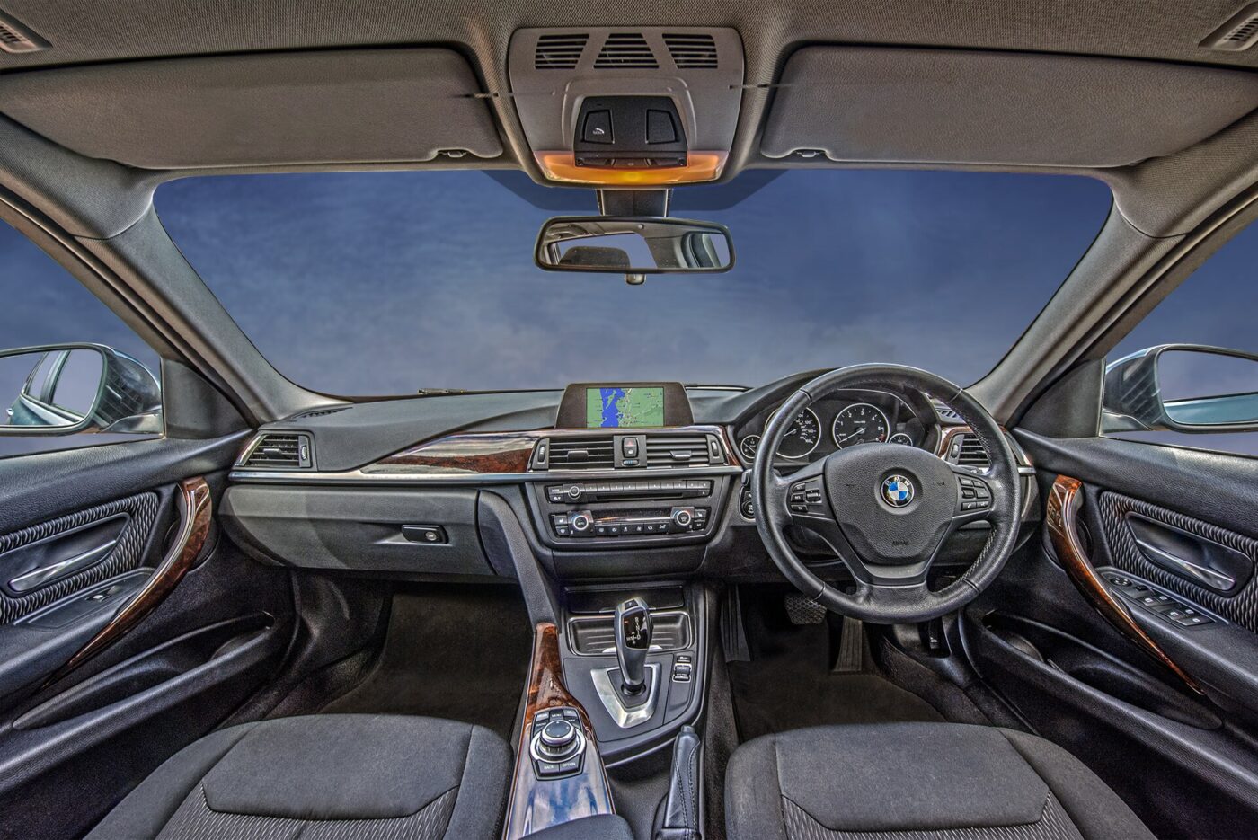 The dashboard, steering wheel and front seats of a modern parked car.