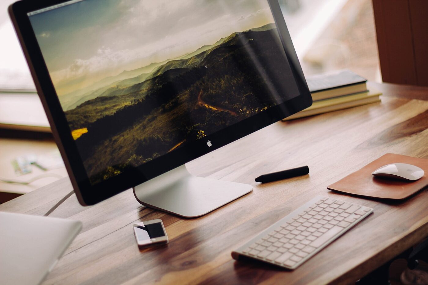 A slim widescreen display with a keyboard and mouse on a wooden desk.