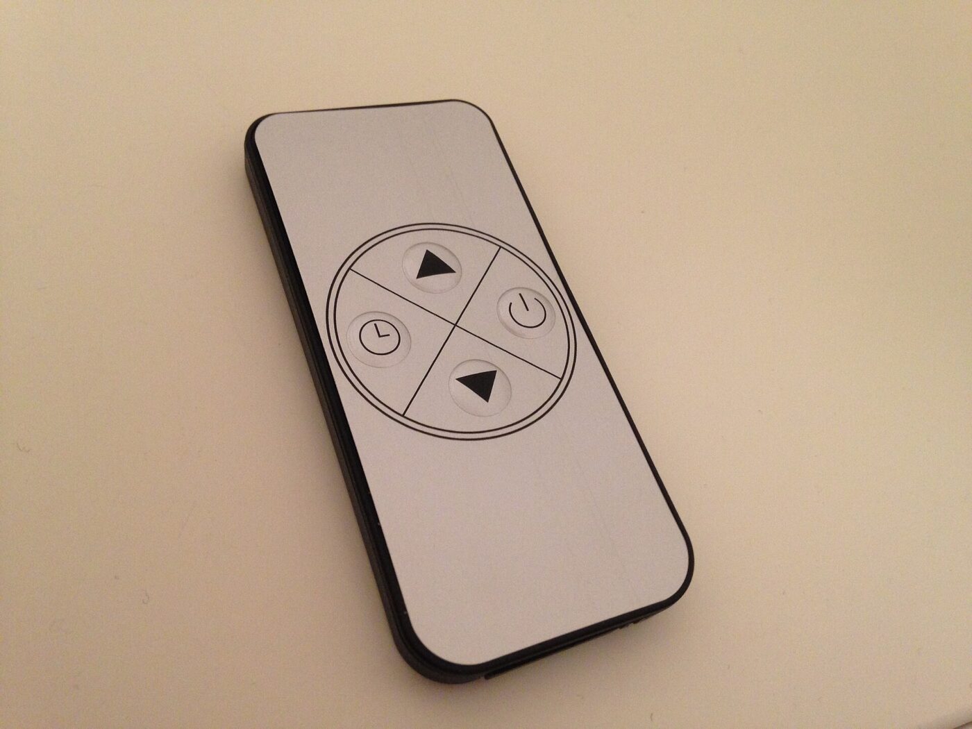 A four-button remote control for a portable heater, with up, down, timer and power keys.