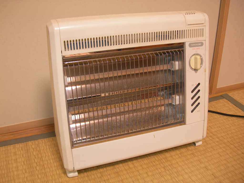 A plug-in radiant heater with two quartz tubes behind a wire guard, standing indoors.