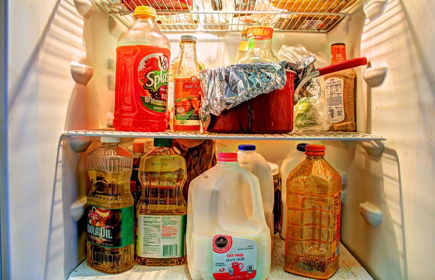 Juice bottles and milk jugs filling the shelves of an open home refrigerator.