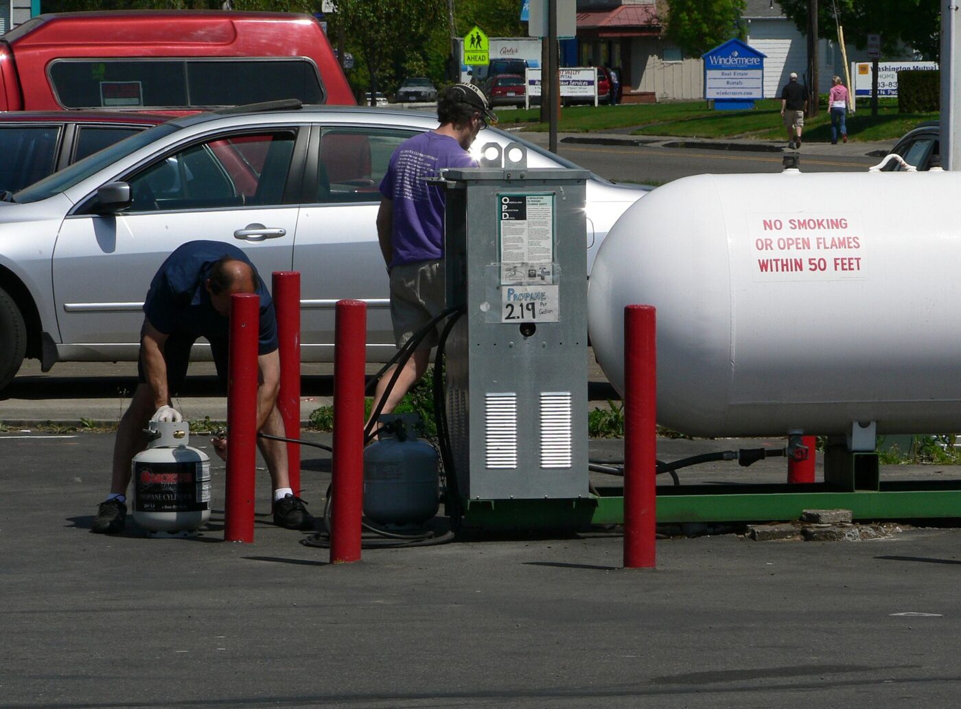 A propane filling point in a retail lot, with a bulk storage tank behind bollards