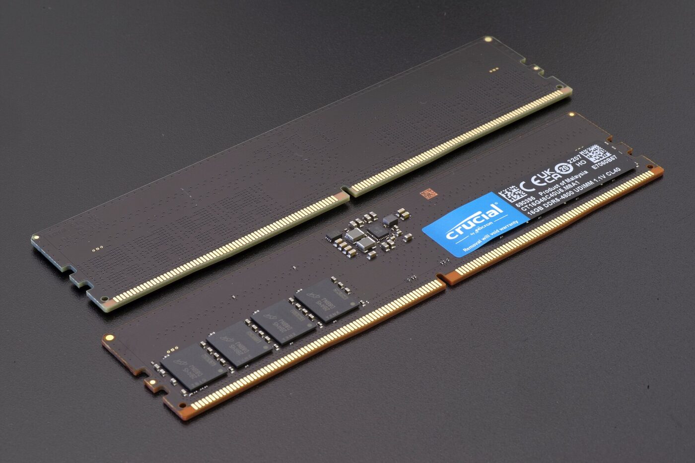 Two DDR5 desktop memory modules on a dark surface, one showing its chips and product label